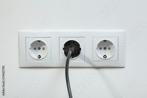 Black power plug plugged in a electric socket