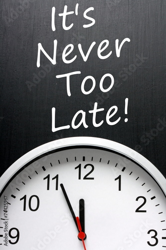 It's Never Too Late written on a blackboard above a clock face
