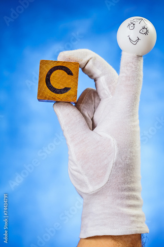 Finger puppet holding wooden cube with capital letter C