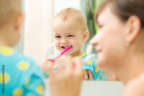 mother and kid look at mirror during teeth brushing