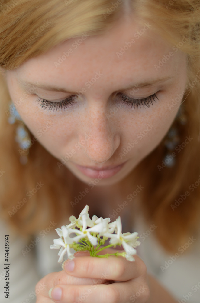 Red-haired girl with freckles looking at white flowers