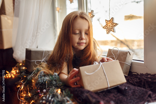 beautiful little girl with gifts on a windowsill