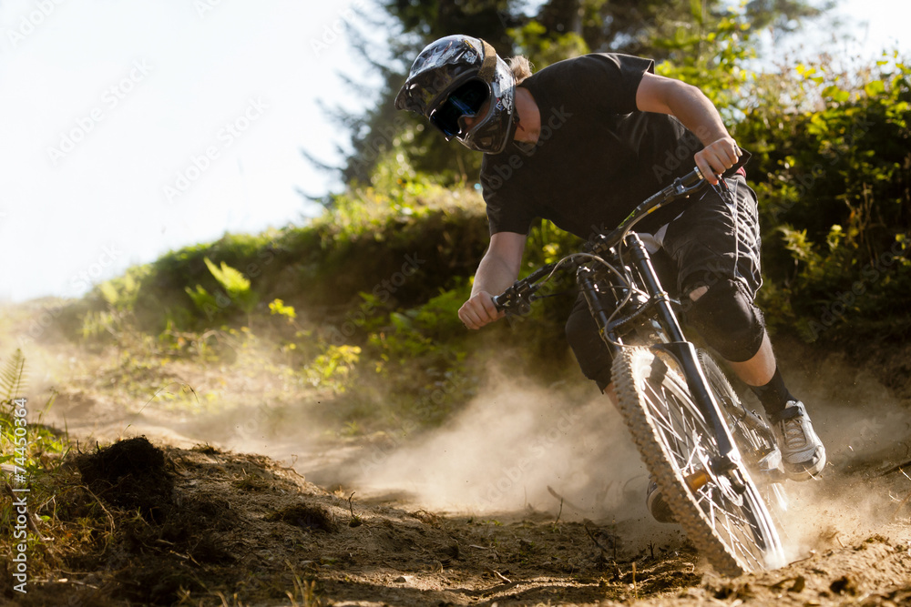 Obraz premium Mountainbiker rides on path in forest