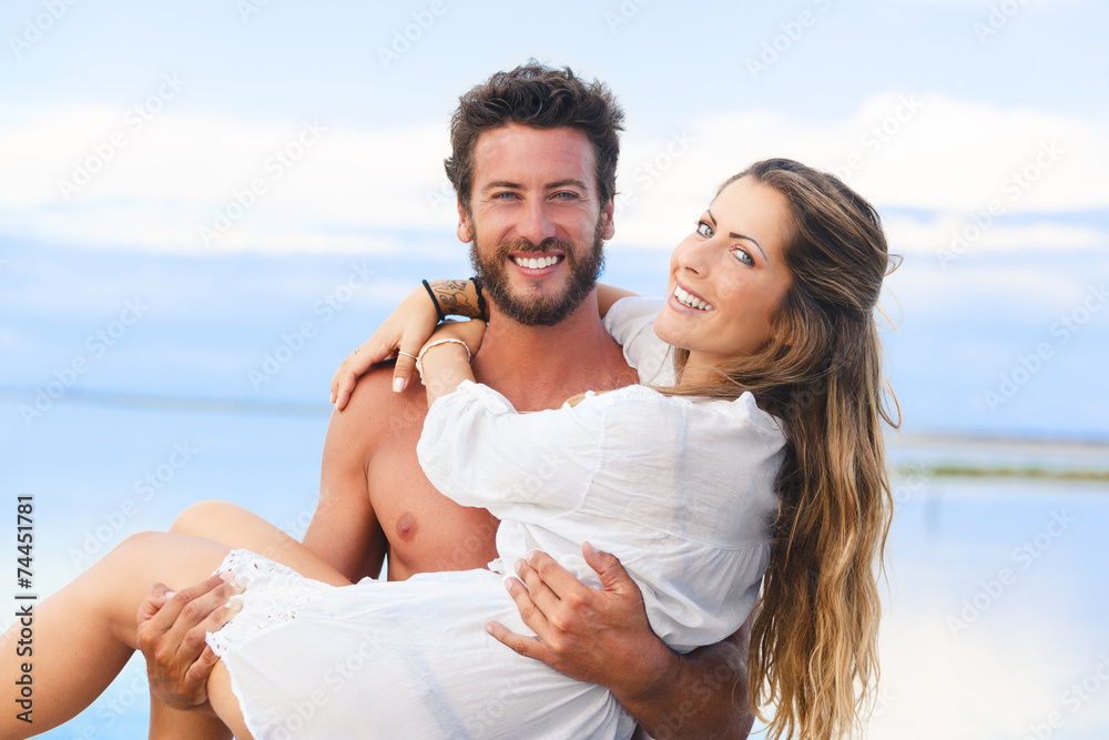 man holding woman in his arms under a blue sky on seaside backgr man holding woman in his arms under a blue sky on seaside backgr