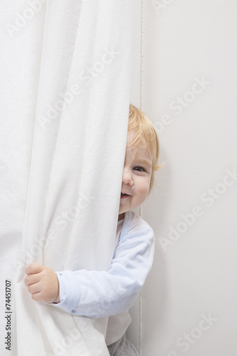 baby peeking behind curtain