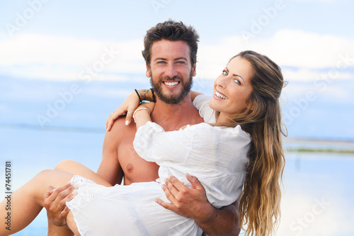 man holding woman in his arms under a blue sky on seaside backgr