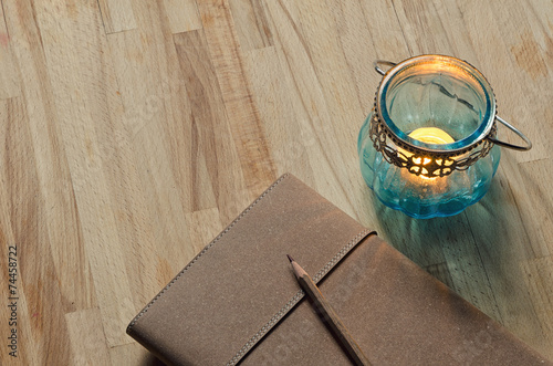 notebook with an old glass candle lantern on wooden table