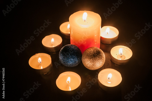 Small candles around a bigger candle and two Christmas globes