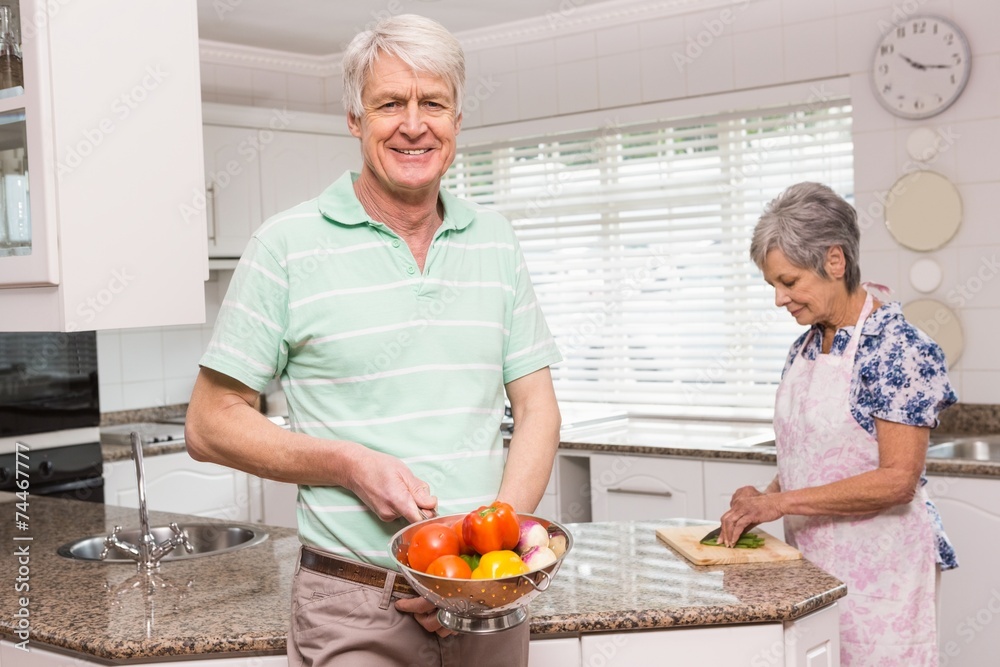 Senior man showing colander of vegetables Senior man showing colander of vegetables