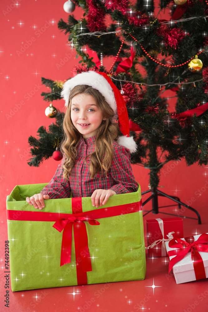 Composite image of festive little girl sitting in large gift Composite image of festive little girl sitting in large gift
