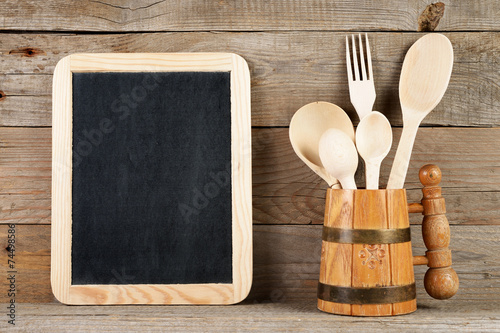Blank blackboard and wooden spoons and fork in mug