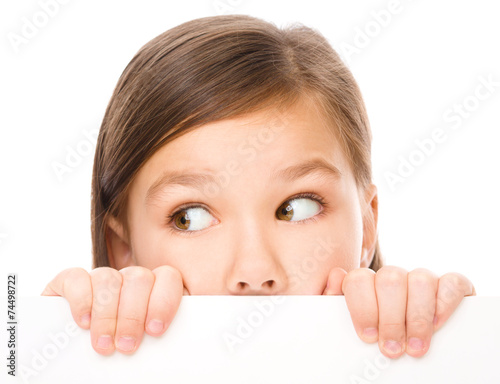 Little girl is looking from out blank board
