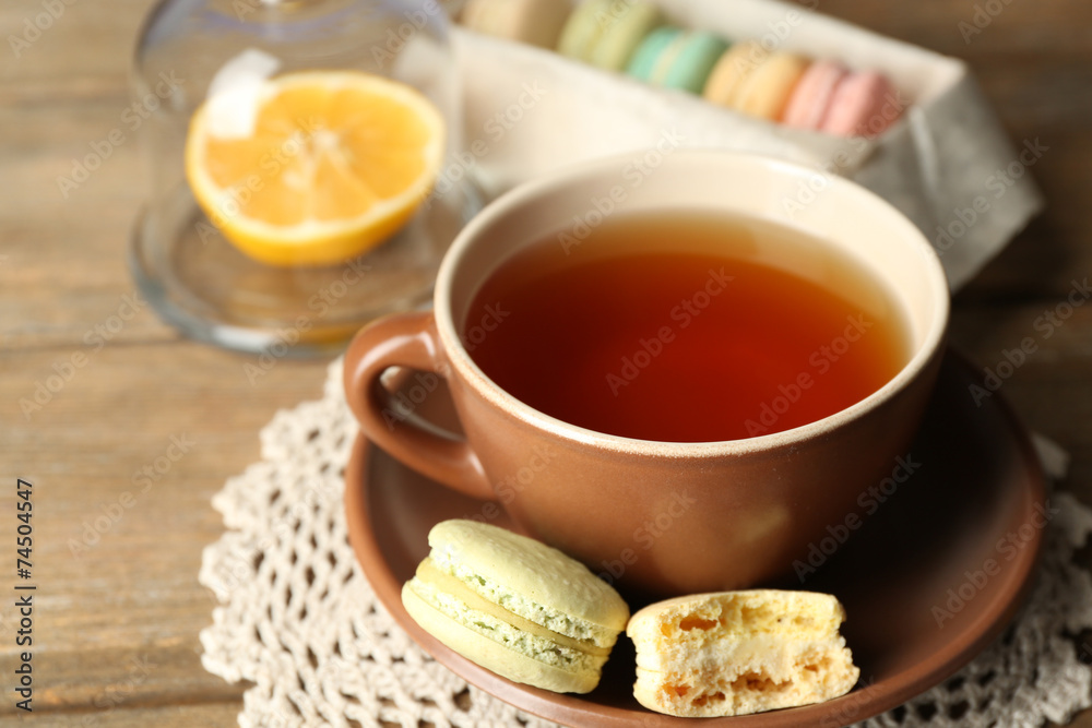 Colorful macaroons with cup of tea on wooden background Colorful macaroons with cup of tea on wooden background