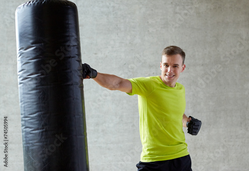 young man in gloves boxing with punching bag