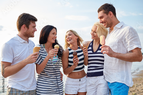 friends eating ice cream and talking on beach