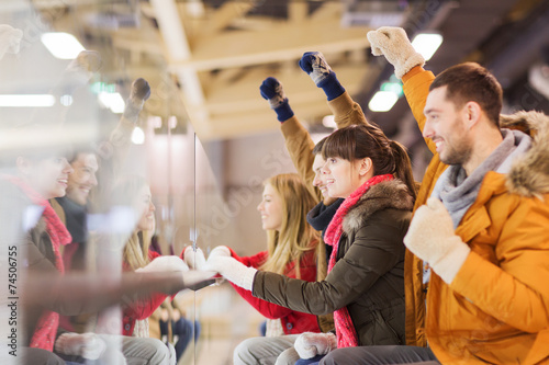 Canvas Print happy friends watching hockey game on skating rink