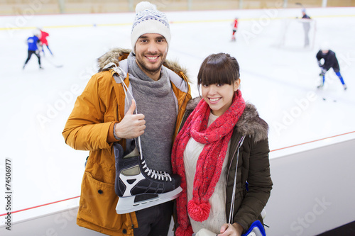 happy couple with ice-skates on skating rink