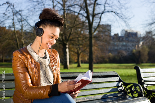 young woman reading a book and listening to music.