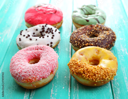 Delicious donuts with glaze on colorful wooden background