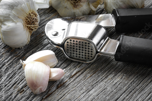 Garlic Press and Garlic Bulb Close Up on Rustic Wood Background photo