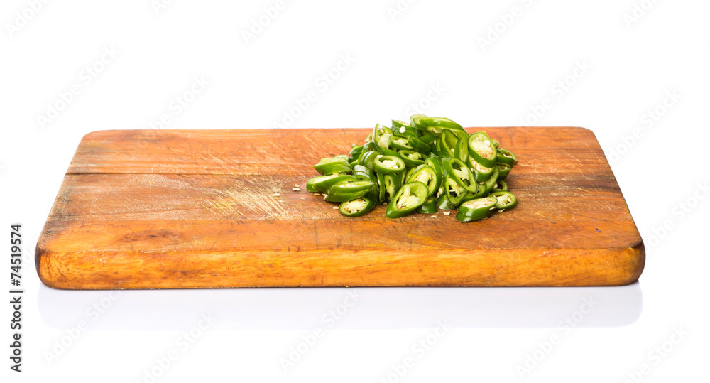 Chopped green chili peppers on wooden cutting board 