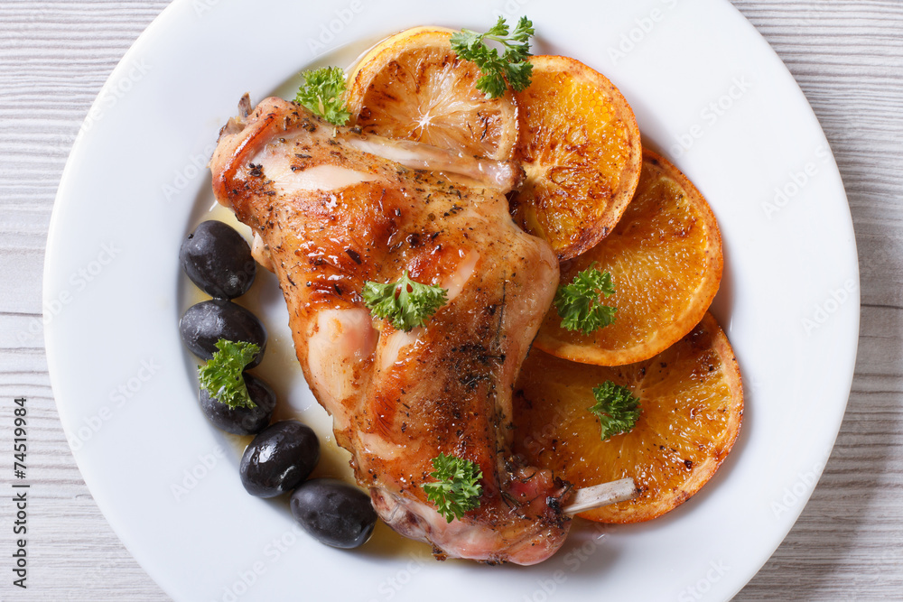 roasted rabbit leg on a plate close-up. horizontal top view roasted rabbit leg on a plate close-up. horizontal top view