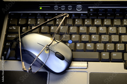 Computer mouse with glasses on keyboard