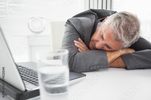 Mature businessman sleeping on desk photo