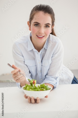 Pretty brunette eating bowl of salad