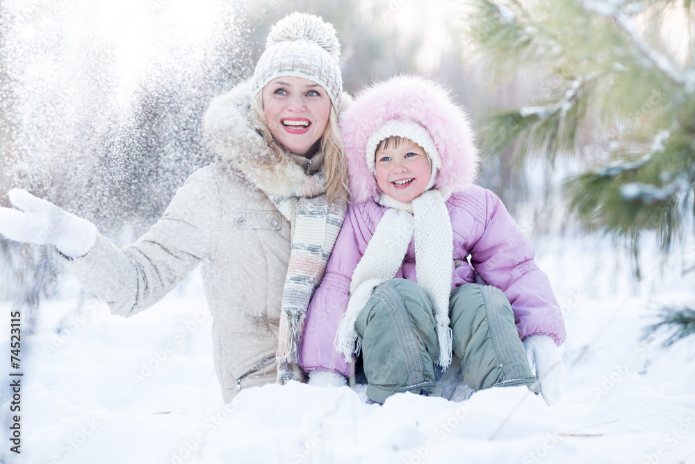 Happy family mother and daughter sitting in snow outdoor