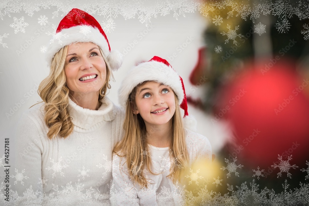 Composite image of festive mother and daughter smiling at tree Composite image of festive mother and daughter smiling at tree