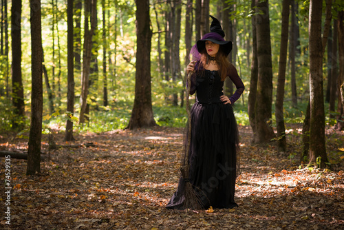 woman in witch s hat holding broom and looking at camera