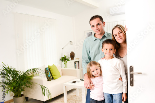 happy family with young kids welcoming a guests at home doorh