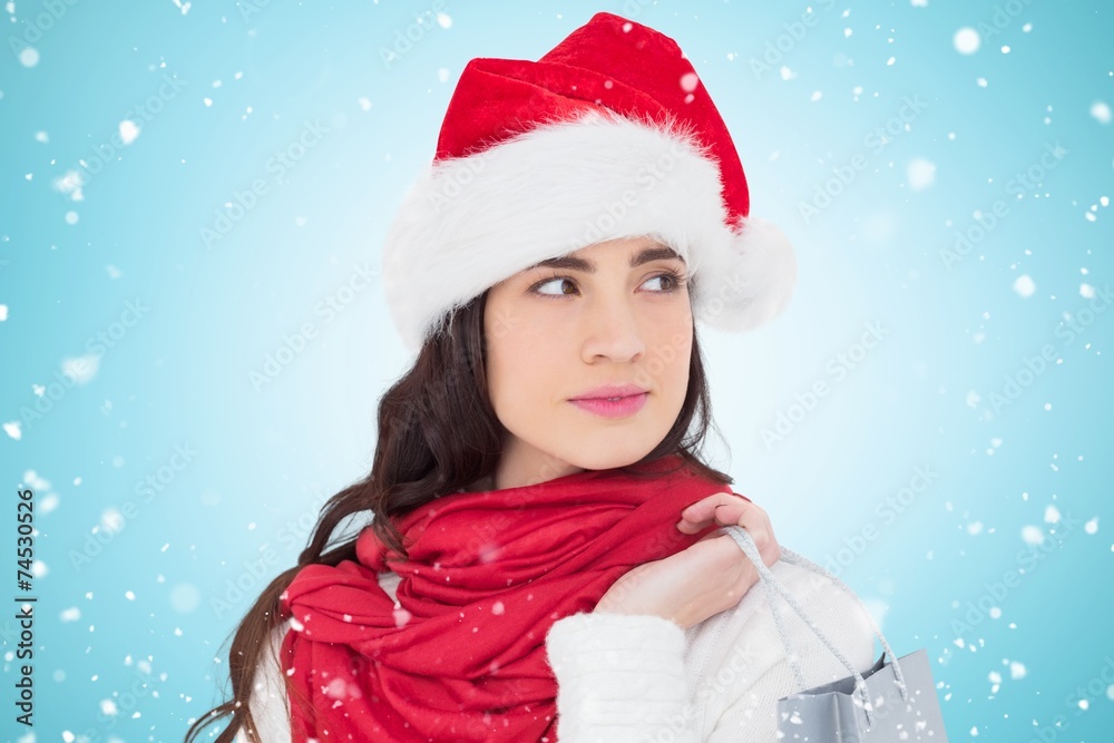 Composite image of brunette in santa hat holding shopping bag Composite image of brunette in santa hat holding shopping bag