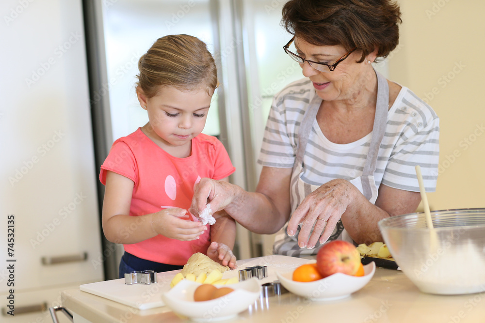 Grandmother with little girl in kitchen baking cookies