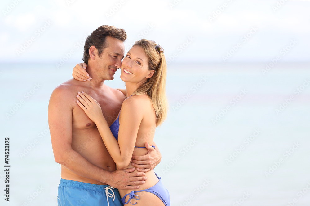 Loving couple in swimsuit embracing at the beach