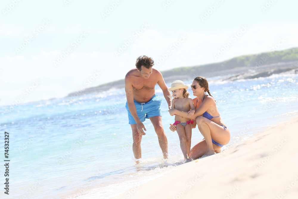 Family of three playing on a sandy beach in summertime