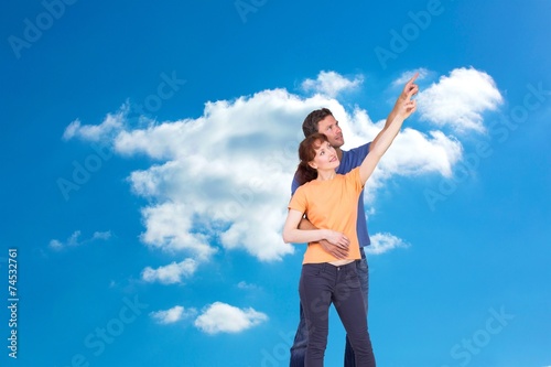 Composite image of happy couple pointing upwards together