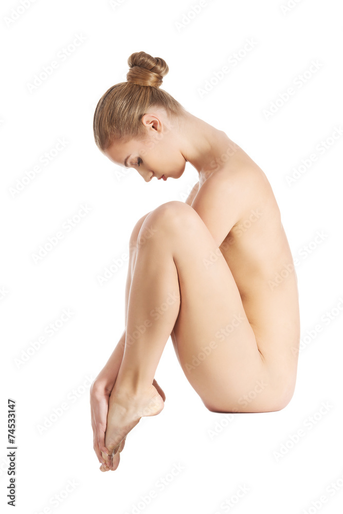 Obraz premium Side view nude woman sitting, holding her toes