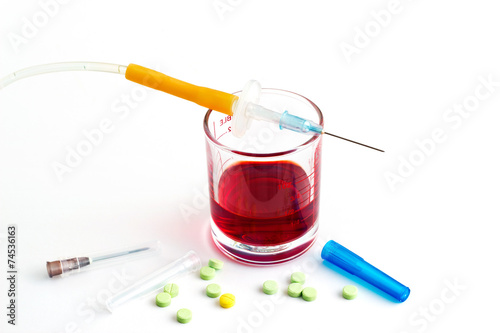 syringe and glass measure and pills on white background
