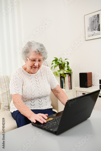cheerful elderly woman websurfing and shopping internet laptop
