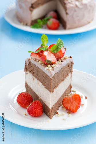 piece of chocolate cake of three layers with fresh strawberries