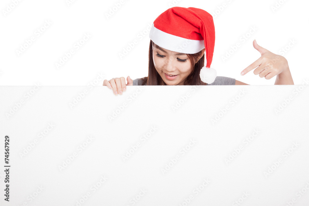 Asian girl with red santa hat look down and point to a blank si Asian girl with red santa hat look down and point to a blank si
