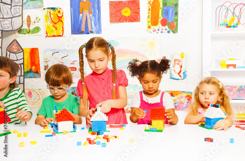 Group of happy kids play with plastic blocks