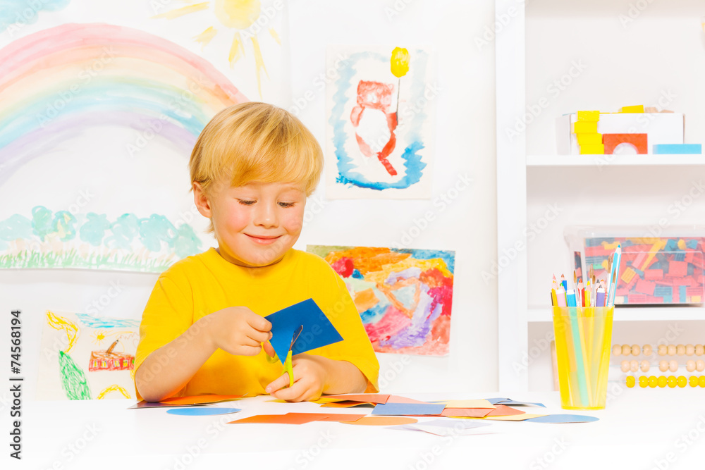 Blond little boy cutting cardboard shape in class Blond little boy cutting cardboard shape in class