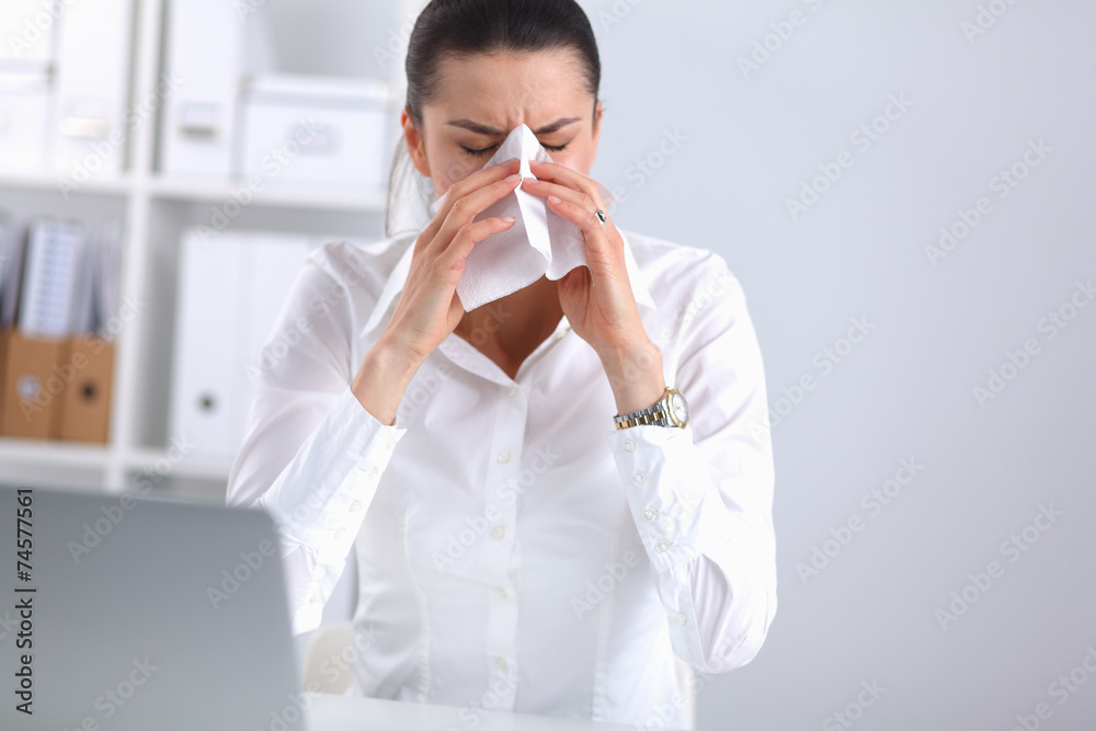 Young businesswoman blowing her nose, sits at the desk Young businesswoman blowing her nose, sits at the desk