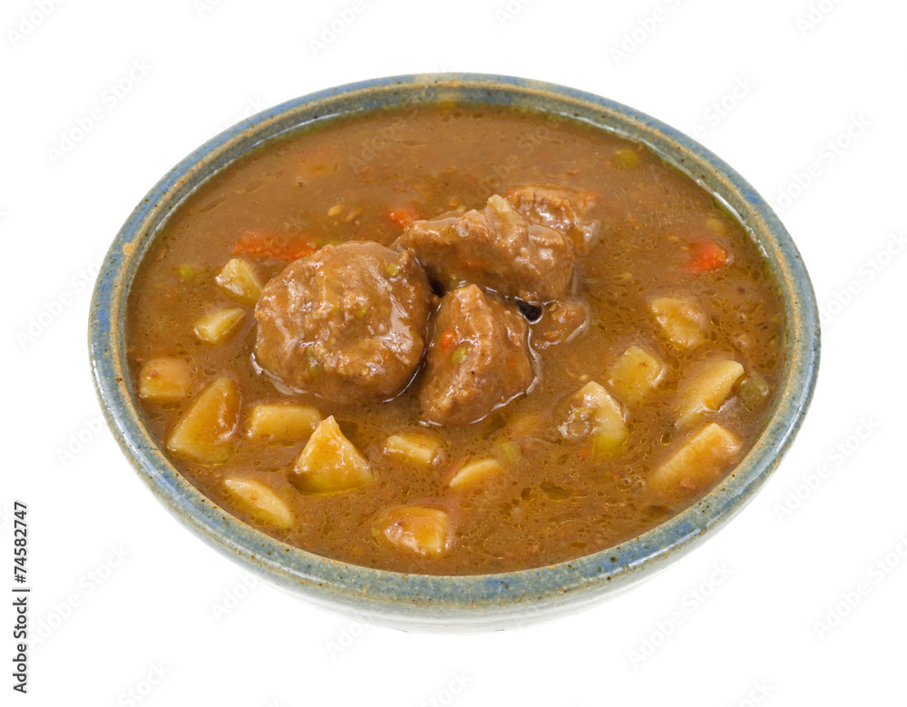 A large serving of meatball stew in an old bowl A large serving of meatball stew in an old bowl