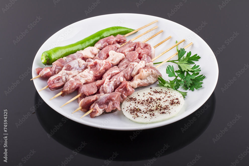 Raw skewer and vegetables on plate Raw skewer and vegetables on plate
