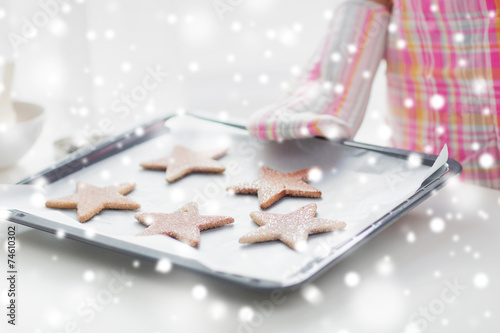 close up of woman with cookies on oven tray