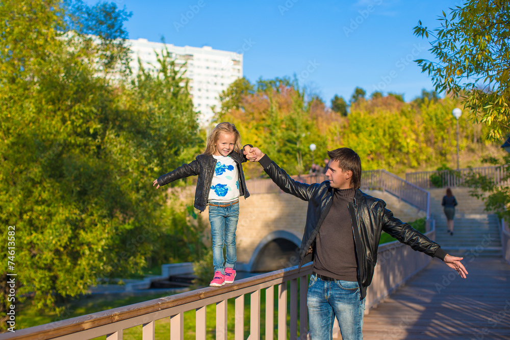 Father and cute daughter in autumn park outdoors